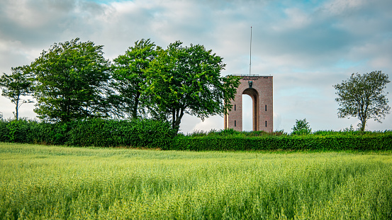 Landscape of green grass field, trees and tower. Denmark highest point, Ejer Bavnehoj.