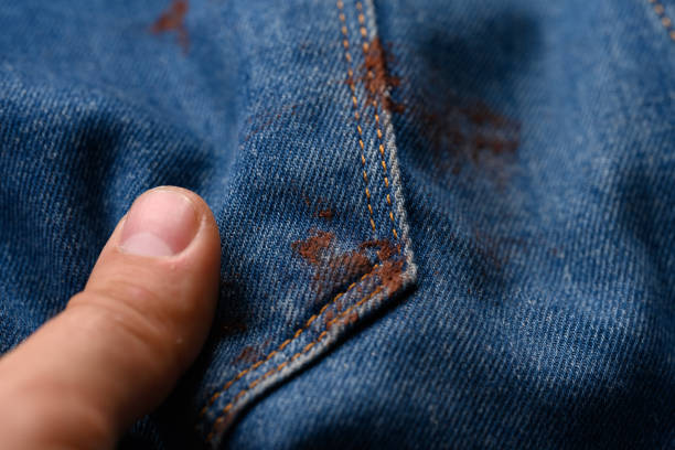 istock Blue jeans stained with brown paint. A man's hand. Close-up 1357159314