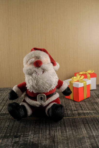 istock Santa claus doll sitting on floor with christmas gift pack background 1357159617