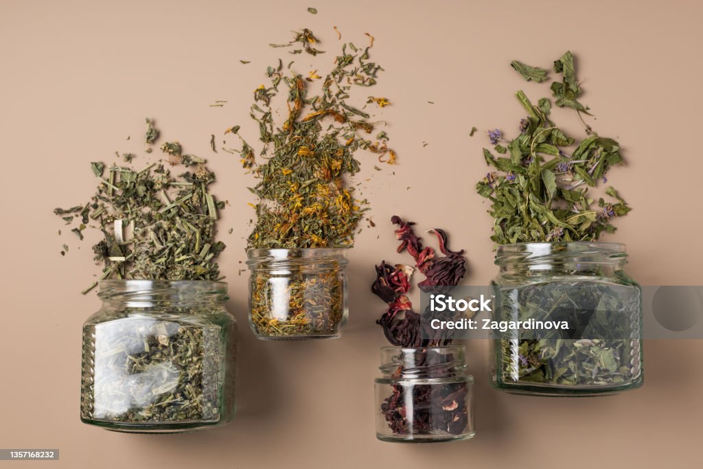 Four Tins of Healthy Dried Herbs Four jars of healthy dried herbs scattered over the background Dried Tea Leaves Stock Photo