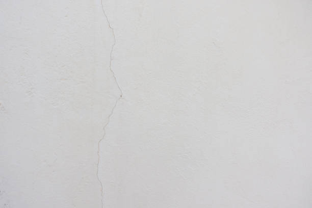 Old blank white grunge painted cracked stucco wall structure texture background.