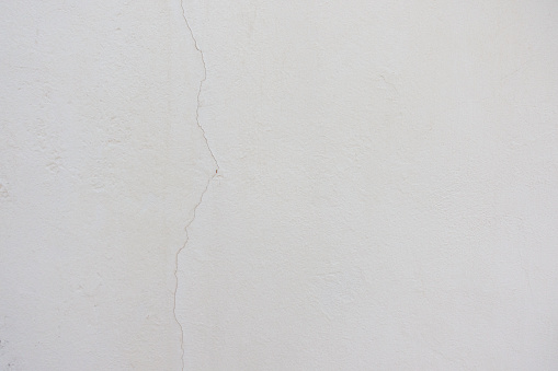 Old blank white grunge painted cracked stucco wall structure texture background.