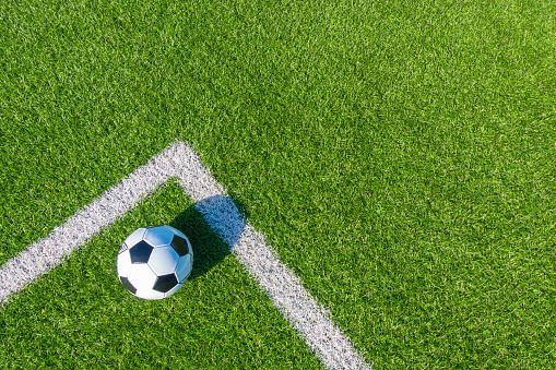 Soccer football sport background. Soccer ball on green artificial grass turf field with white line. Top view.