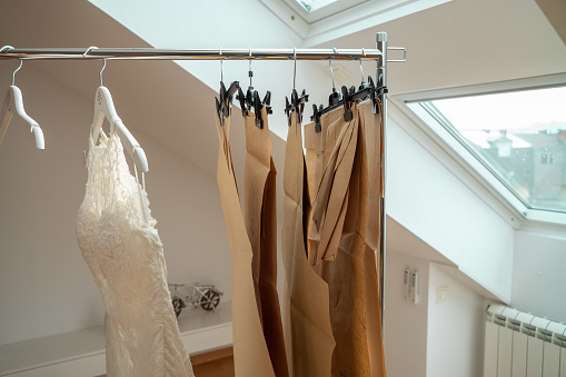 Wedding dress and coathangers hanging on clothing rack in bridal design studio