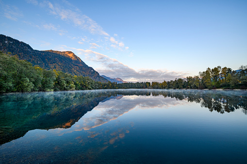 Idyllic lake with calm water and the reflection of the mountains at sunrise. Vorarlberg, Nuziders