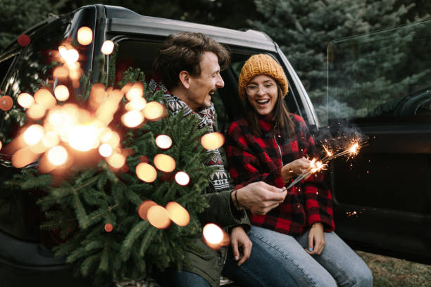 istock Couple having fun with sparkle on Christmas tree adventure 1357179867