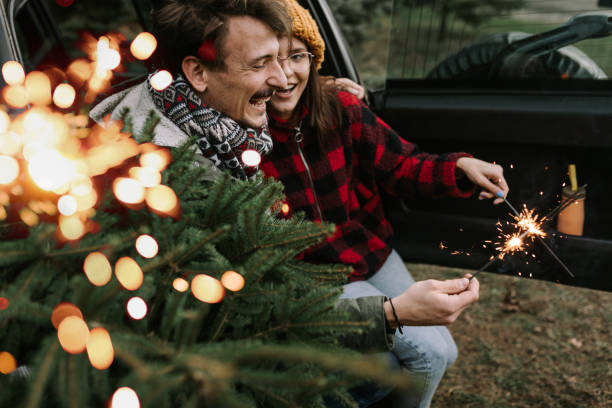 istock Couple having fun with sparkle on Christmas tree adventure 1357179920