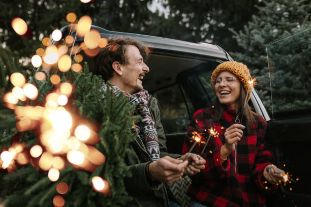 Couple having fun with sparkle on Christmas tree adventure