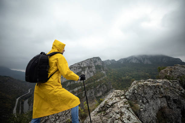 istock Hiker in a yellow raincoat climbing a mountain 1357182635