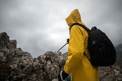 Climber in a yellow raincoat climbing a mountain
