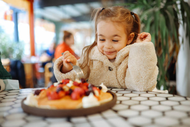 Little girl eating breakfast crepes with fruits Little girl having crepes for breakfast. The crepes are sprinkled with fruits - blueberries and raspberries. Sweet toddler birthday boy, eating belgian waffle with raspberries and chocolate at cafe kids restaurant pictures stock pictures, royalty-free photos & images