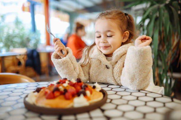 Little girl eating breakfast crepes with fruits