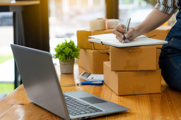 istock Young woman working at home with box and laptop taking orders from customers online work concept sme ready to deliver parcels 1357215465