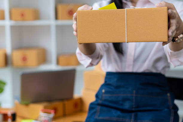 istock Young woman working at home with box and laptop taking orders from customers online work concept sme ready to deliver parcels 1357215518