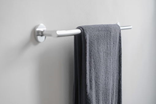 Close-up shot of a clean gray towel hanging on a stainless steel towel rail of a clean bathroom.