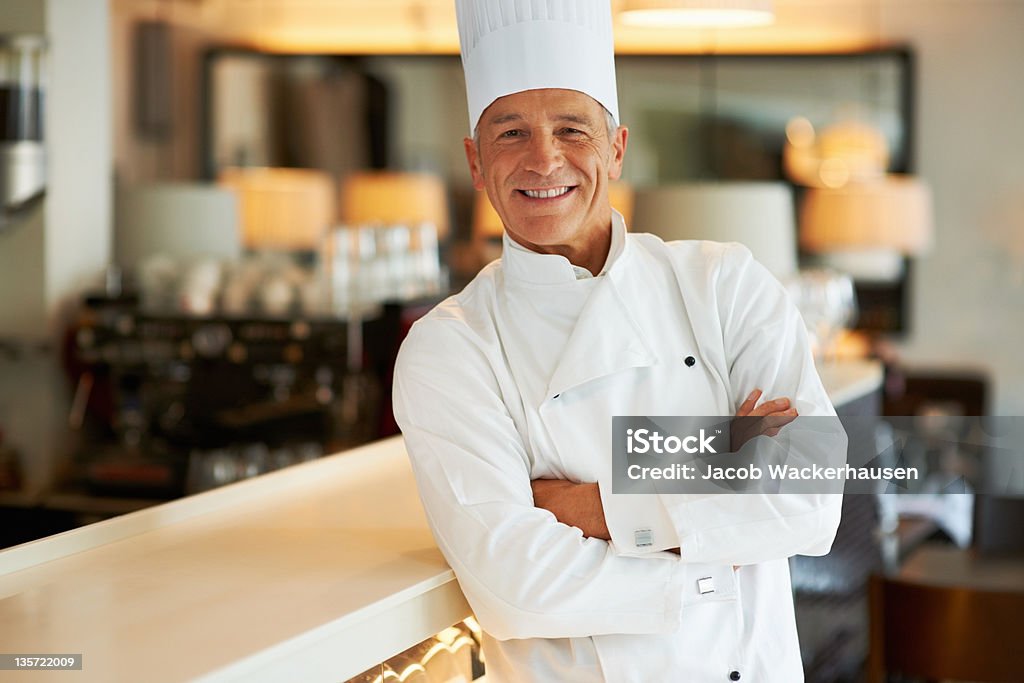 Successful chef Portrait of a smiling chef standing with arms crossed in his restaurant Chef Stock Photo