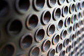Tube sheet or plate of boiler or heat exchanger selective focus shot at an angle closeup texture industrial background, with insoluble hard mineral deposits salts scale and corrosion with copyspace.