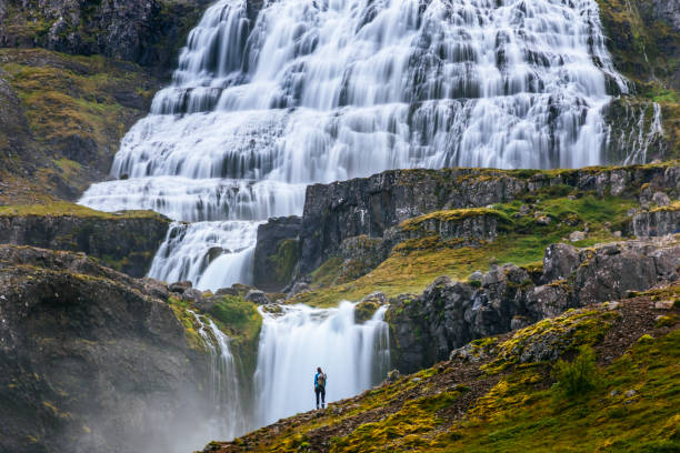 istock A woman is standing in front of a waterfall in Iceland. 1357230647