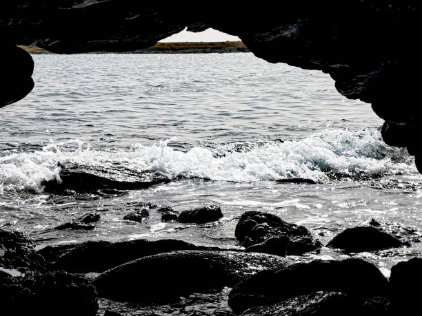 Waves splashing on the rocks. Atlantic Ocean lagoon in Cape Verde. Shark bay in Espingueira. Natural arch. Selective focus on the details, blurred background.