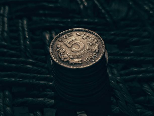 Stock photo of a man holding five rupees coin Indian currency on blur background at Bangalore, Karnataka, India. focus on object