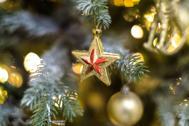 istock golden toy star on christmas tree with blurred lights 1357235459