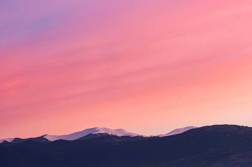 Stunning view of a snowcapped mountain range during a beautiful sunrise.