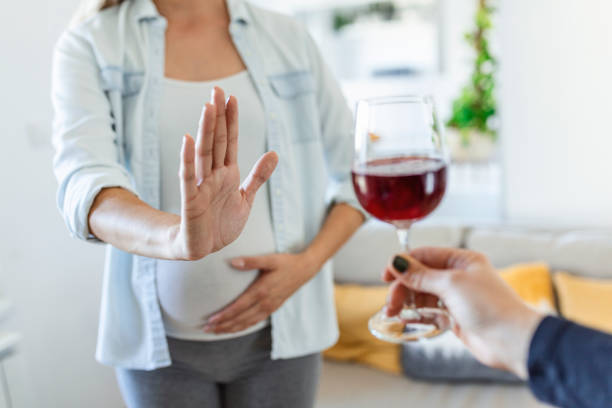 mujer embarazada que rechaza una copa de vino. alcohol en el embarazo. expectante irreconocible lady gestring se detiene para ofrecer una copa de vino - baby shower women home interior indoors fotografías e imágenes de stock