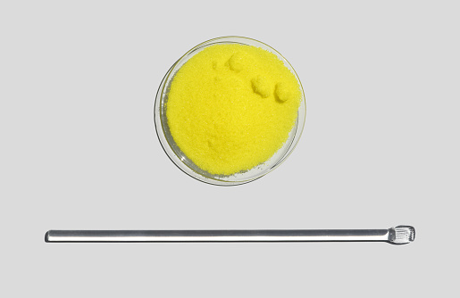 Potassium Chromate Powder in Chemical Watch Glass place next to stirring rod. Closeup chemical ingredient on white laboratory table. Top View