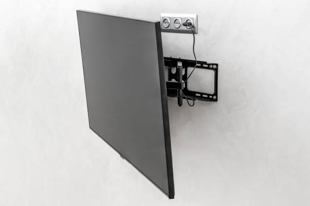 Modern tv hanging on the wall. Tv mounted with special fasteners in the room. stock photo