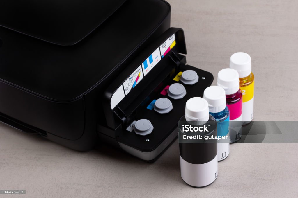 inkjet four-color printer with continuous ink supply and ink bottles for refilling on grey background close-up Ink Stock Photo