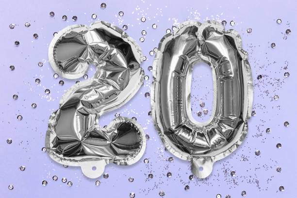 istock Silver foil balloon number, digit twenty on a lilac background with sequins. Birthday greeting card with inscription 20 1357249662