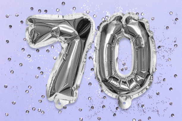 istock Silver foil balloon number, digit seventy on a lilac background with sequins. Birthday greeting card 1357250177