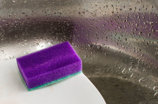istock sponges and dish washing liquid soap on dirty sink. 1357253053