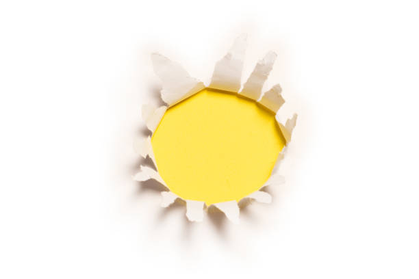 istock A hole in a white paper on a yellow background. 1357257615