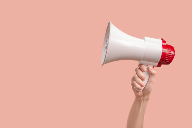 istock Megaphone in woman hands on a pink background. 1357257649