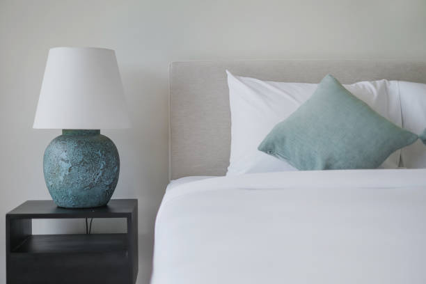 Clean Minimalist Bedroom Shot of clean minimalist bedroom design. There's a turquoise loose pillows and a nice ceramic vase side lamp. bed decoration stock pictures, royalty-free photos & images
