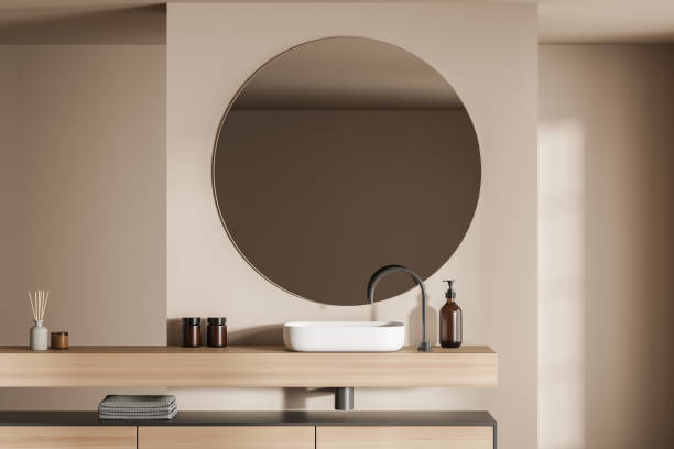 istock Beige bathroom vanity area with round mirror 1357261444