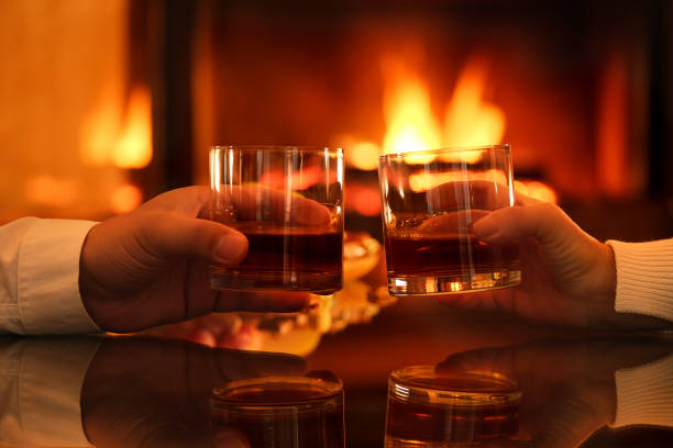 Young couple has romantic dinner with whiskey over fireplace background. stock photo