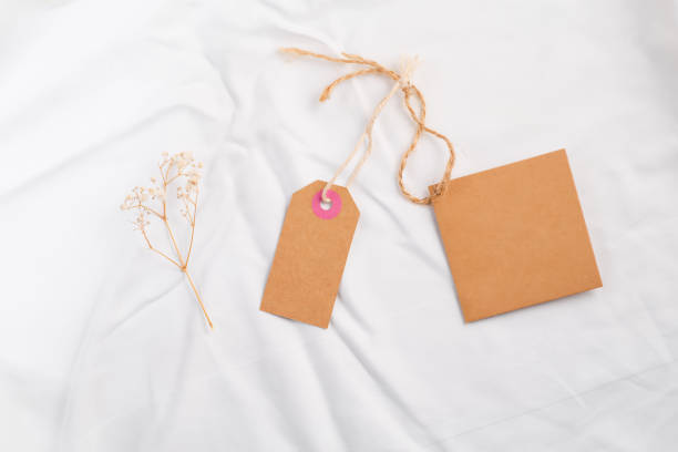 istock Mockup hanging gift tags eco-friendly kraft paper with dry flower on silk 1357264714