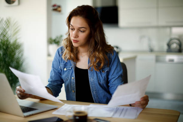 jeune femme sérieuse travaillant à la maison - paperwork photos et images de collection