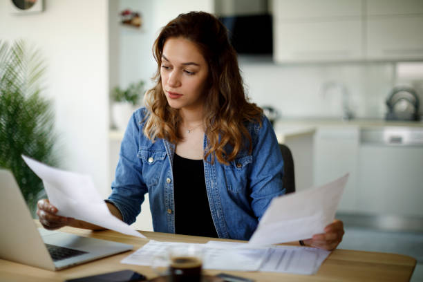 Serious young woman working at home Serious young woman working at home income tax stock pictures, royalty-free photos & images