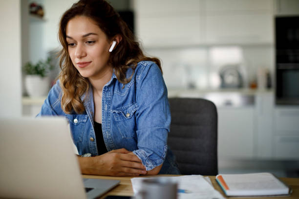 młoda kobieta ze słuchawkami bluetooth mająca wideokonferencję w domu - online lesson zdjęcia i obrazy z banku zdjęć