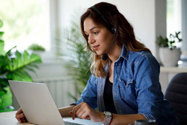 istock Young woman using a headset and laptop at home office 1357264867