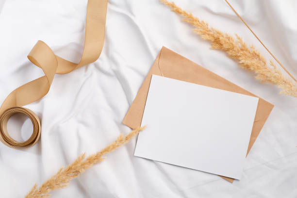 istock Styled craft envelope and white card mockup with dried grass on textile 1357265821