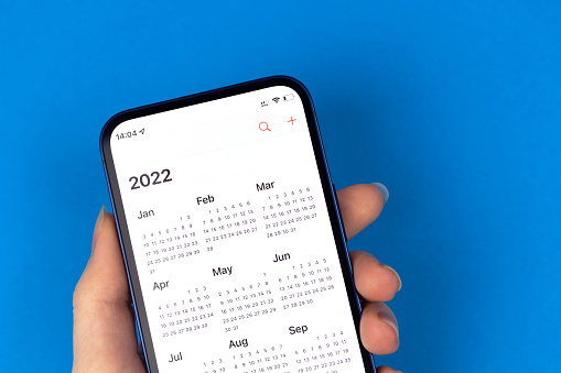 Calendar for 2022 on smartphone screen. Close-up view. New year planning concept