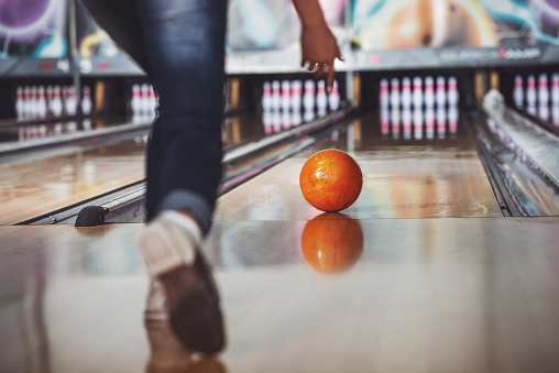 Woman in club for bowling is throwing ball.