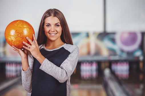 Smiling young woman in a bowling alley is having fun.