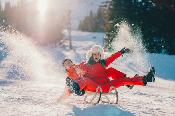 istock Joyful couple sledding on winter holiday 1357273306