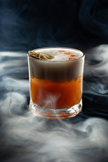 Whiskey stout sour in smoke Whiskey stout sour in smoke on black background glass of bourbon stock pictures, royalty-free photos & images