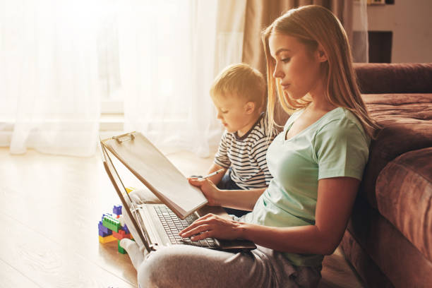 istock Young woman with child studying on laptop, making notes 1357276735